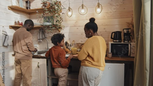 Modern Black family with kid spending time together in country house kitchen cooking lunch, watching dishes and chatting