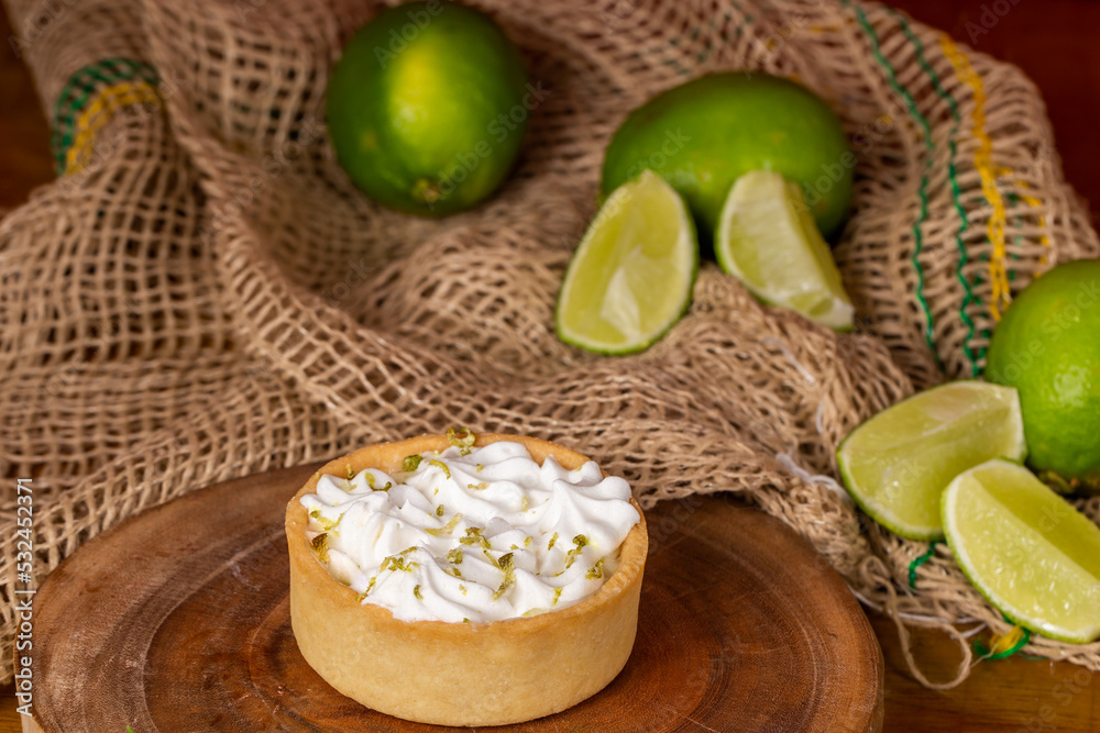 mini lemon pie topped with whipped cream and lemons in the background mini lemon pie topped with whipped cream and lemons in the background