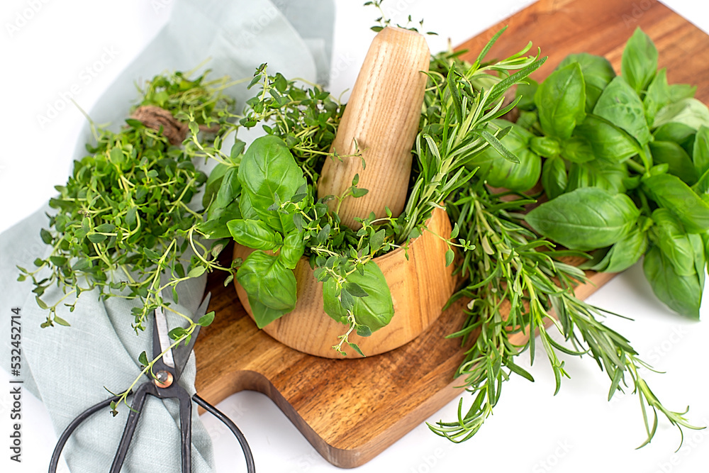 Mix of fresh herbs rosemary, thyme, basil with wooden mortar on wooden board. Top view. Copy space