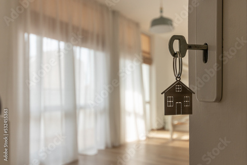 Open door to a new home with key and home shaped keychain. Mortgage, investment, real estate, property and new home concept photo