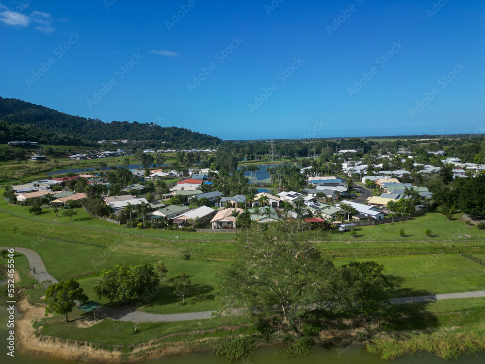 Obraz premium Aerial view of tropical housing estate with mountains, blue sky and a lake