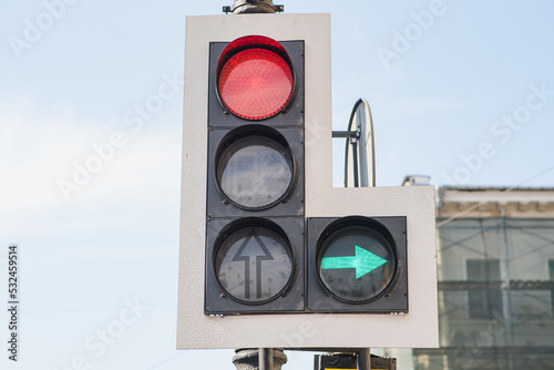 Close-up of a traffic light with a red light and a green arrow pointing to the right side.