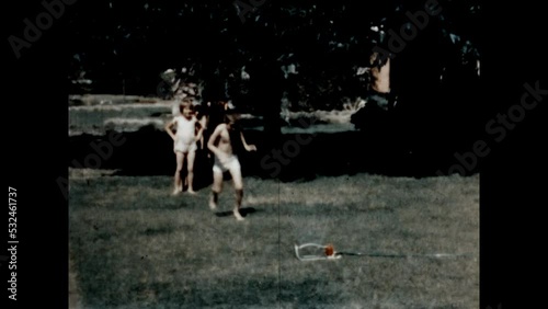 Running Through the Sprinkler 1967 - Siblings take turns running through a lawn sprinkler at their home in Canoga Park, California in 1967. photo