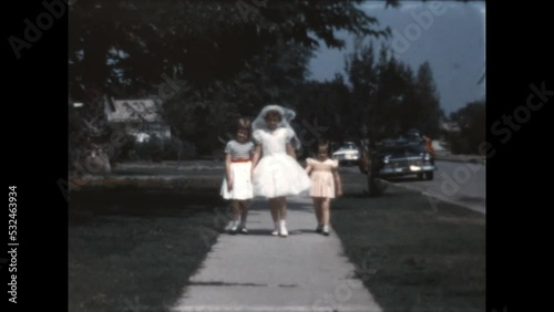 Sisters Hold Hands 1966 - Sisters hold hands as they approach the camera before the eldest's First Communion in Canoga Park, California in 1966.  photo