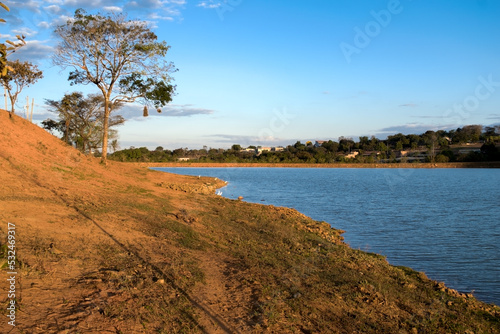 Linda paisagem com nuvens e árvores, com céu azul e limpo, em frente a lagoa no bairro Jardim das Oliveiras, Esmeraldas, Minas Gerais, Brasil.