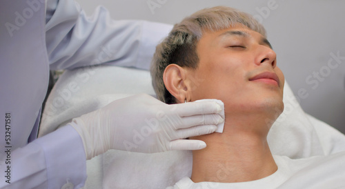 A handsome Asian man undergoes facial rejuvenation in a beauty clinic using modern medical equipment. By certified beauty experts according to standards.