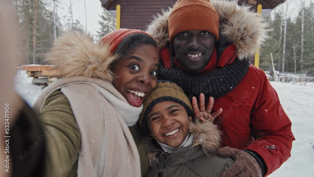 African American man, woman and their preteen son standing outdoors on winter day recording video on smartphone camera African American man, woman and their preteen son standing outdoors on winter day recording video on smartphone camera