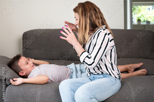 Loving mother tickling her little son on the sofa at home. High quality photography