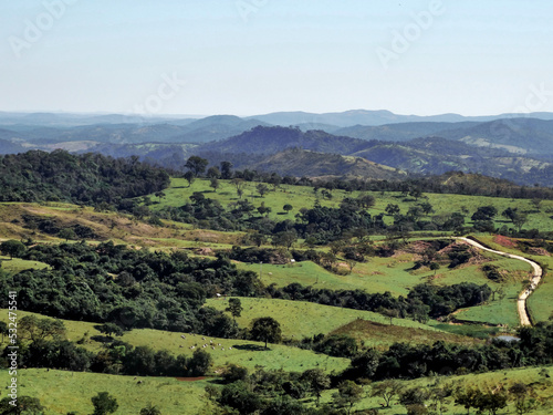 Linda vista de fazenda, com lago artificial, muita vegetação, montanhas ao redor e uma estrada no meio. localizada na região rural do bairro Jardim das Oliveiras, município de Esmeraldas, Minas Gerais