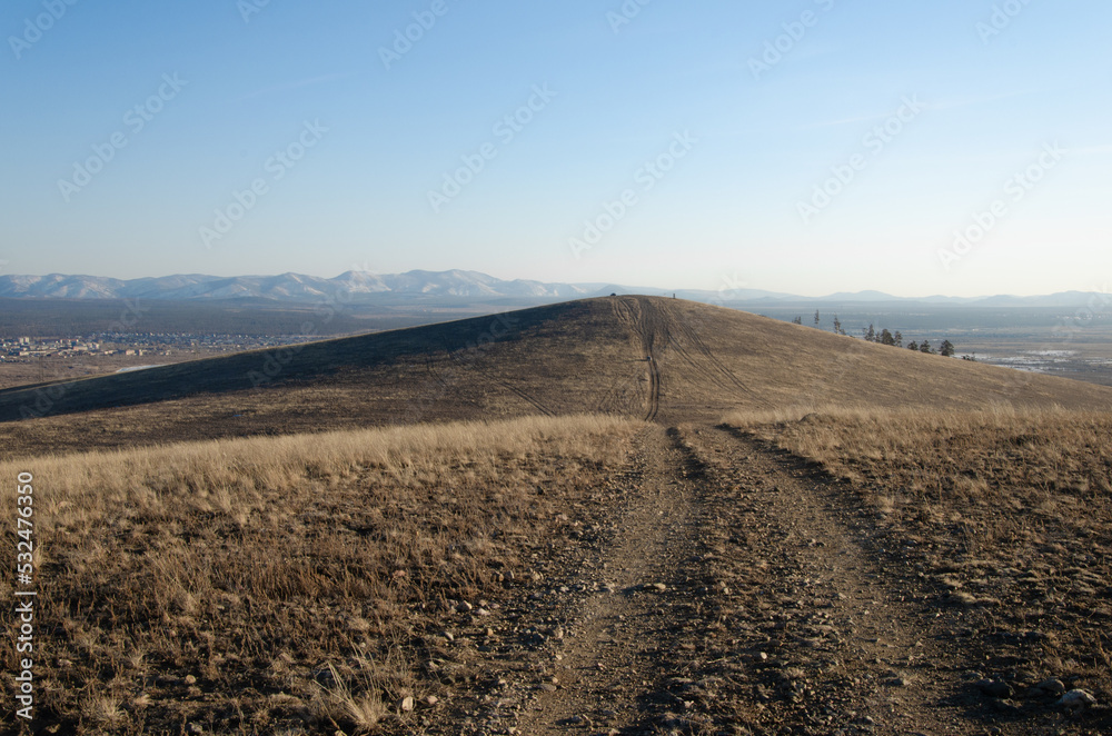 Dirt road through the hills. Autumn, mountainous terrain in the steppe, through which the road runs.
