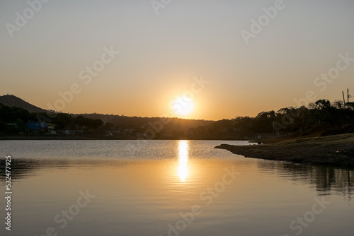 Lindo pôr do sol ao entardecer com céu limpo, com reflexo em lago no bairro Jardim das Oliveiras, Esmeraldas, Minas Gerais, Brasil.