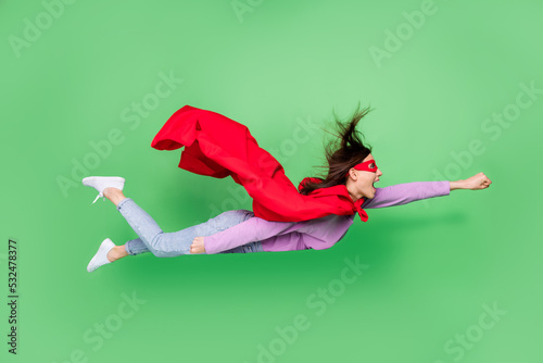 Full size photo of young sporty energetic girl crazy fist up fly fast speed superhero adventures against evil isolated on green color background photo