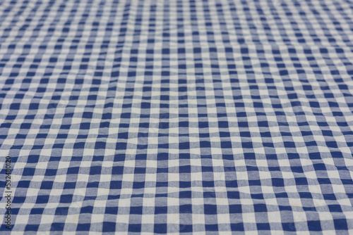 Selective focus and close up shot of white-blue checker pattern fabric on table shows beautiful detail woven textile. It is retro or vintage background or backdrop for traditional scottish garment.