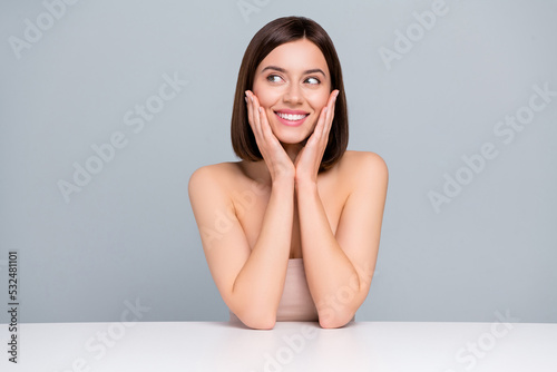 Photo of lady sit table touch hands cheeks look empty space plastic surgery rejuvenating advert isolated over grey color background