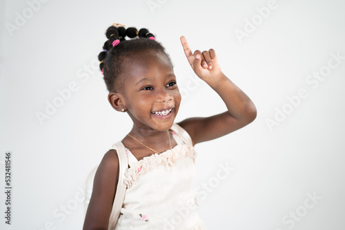 Una ragazzina sorridente in età scolare attira l'attenzione alzando il dito indice e indicando un posto per una scritta per pubblicità e sconti. Isolato su sfondo bianco photo