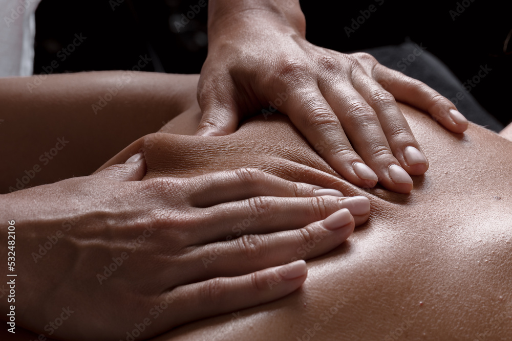 Fototapeta premium masseur girl makes a massage close-up on a dark background. close-up massage