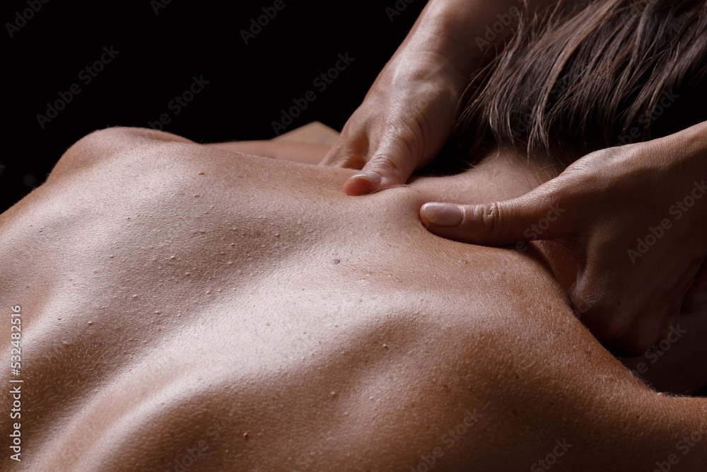 masseur girl makes a massage close-up on a dark background. close-up massage masseur girl makes a massage close-up on a dark background. close-up massage