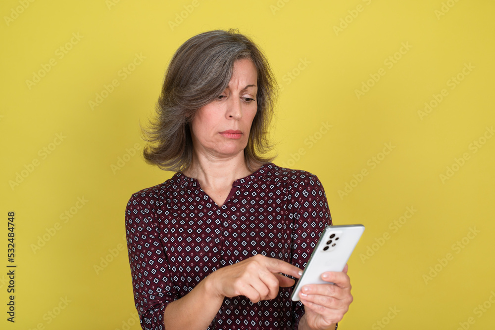 Pensive mature woman reading text message on cell phone Pensive mature woman reading text message on cell phone