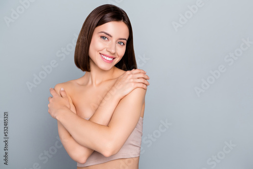 Photo of smiling stunning feminine girl hug her naked shoulders body care cosmetics enhancements isolated on grey color background photo