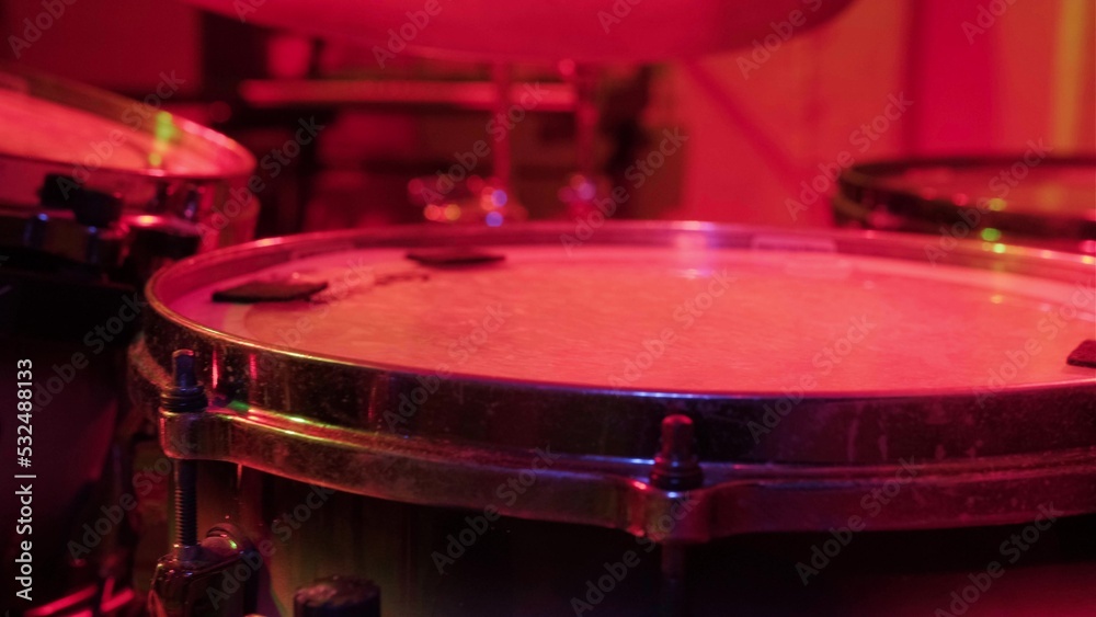 Obraz premium Drummer rehearsing on drums before rock concert. Man recording music on drum set in studio in red light
