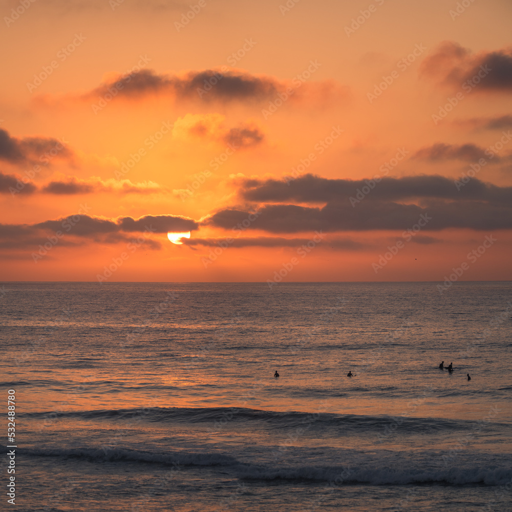 Surfer silhouettes in the ocean at sunset