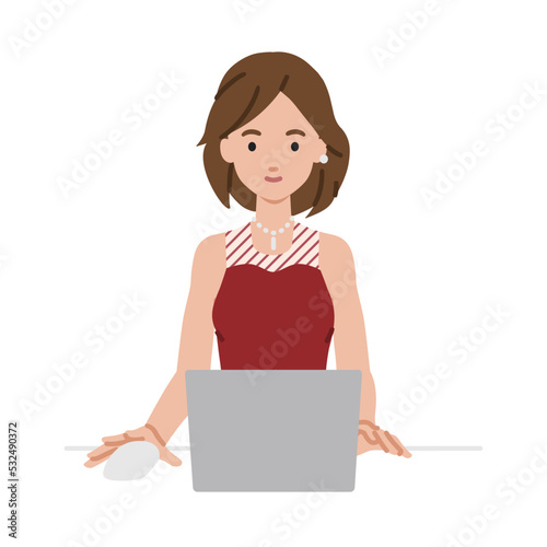 デスクで座ってPCを使っているドレスの女性