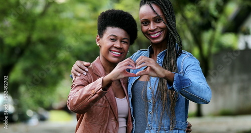 Friends making heart symbol together standing outside, african women coming together