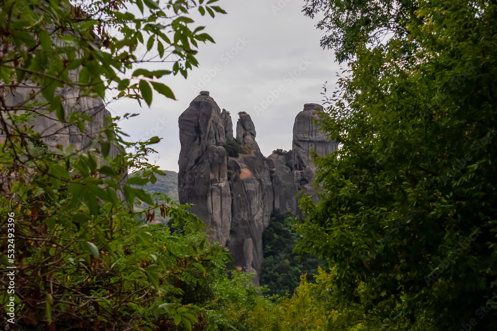 Panoramic view of the unique rock formations near village Kastraki on a mystical cloudy day in Kalambaka, Meteora, Thessaly district, Greece, Europe. Watching from the forest through tree branches