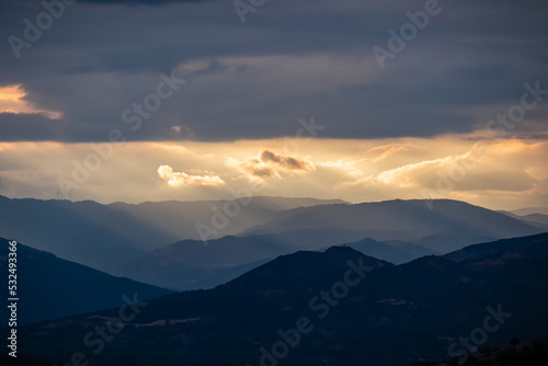 Panoramic view during sunset from Meteora rocks to Pindos mountains, the biggest mountain range of Greece, Thessaly district, Greece, Europe. Soft sun beam through clouds reaching the summit tops