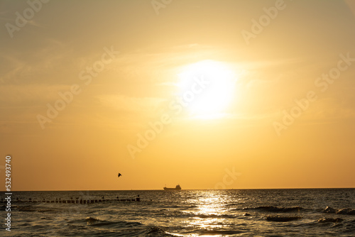 Fototapeta Naklejka Na Ścianę i Meble -  Sunset over the sea with a ship on the horizon