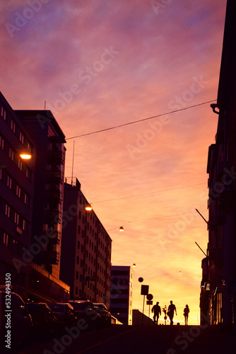 City street view of silhouettes on sunset sky