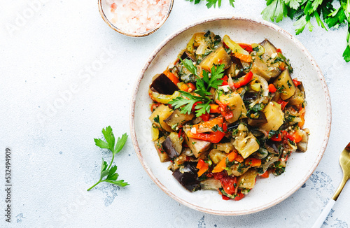 Vegetable stew, saute or caponata. Stewed eggplant with paprika, tomatoes, spices and herbs. White kitchen table background, top view, copy space