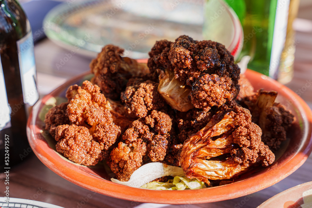Obraz premium Traditional Middle Eastern dish. Appetizer of baked cauliflower and pomegranate sauce. Elegant taste. Lebanese cuisine. Unusual combination of flavors, healthy snack, golden crust.
