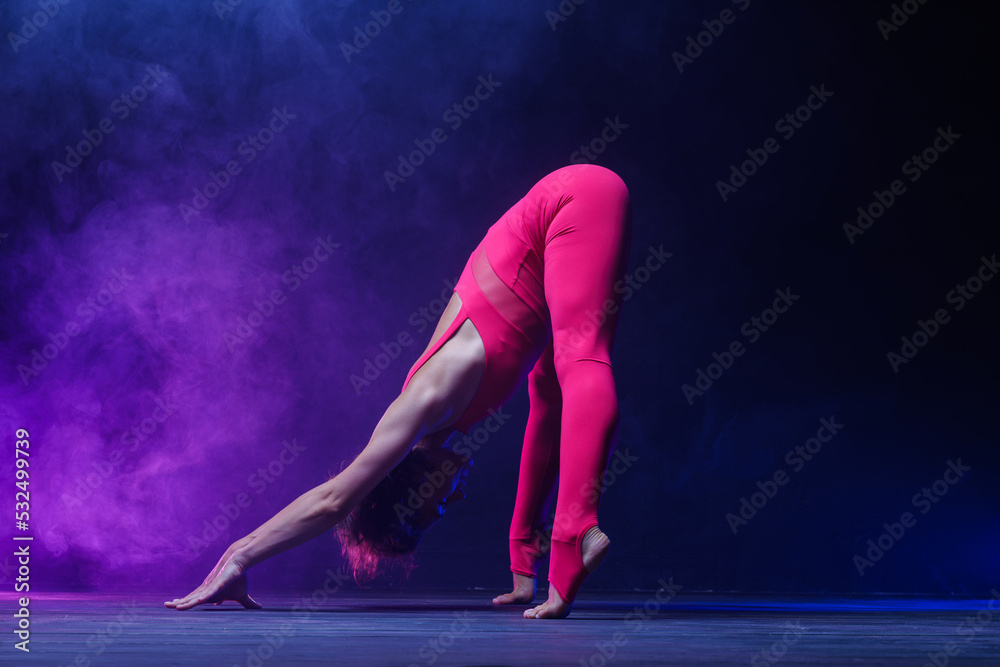 the girl is engaged in stretching on a dark background, a stylish photo of fitness and yoga. Copy space the girl is engaged in stretching on a dark background, a stylish photo of fitness and yoga. Copy space