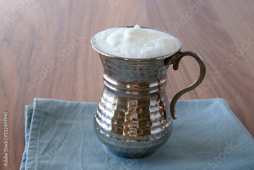 Ayran - Buttermilk. Traditional Turkish yoghurt drink with foam in a copper metal cup. Copy space for text