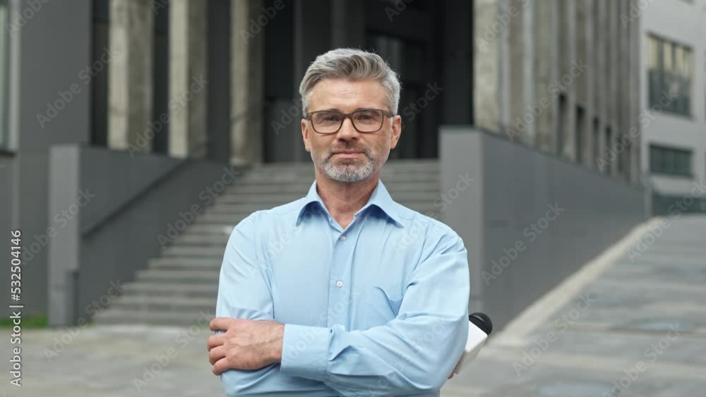 Close up of Caucasian handsome male correspondent standing with microphone in street near government building. Newsman standing outdoors looking and smiling to camera. Journalism concept Close up of Caucasian handsome male correspondent standing with microphone in street near government building. Newsman standing outdoors looking and smiling to camera. Journalism concept