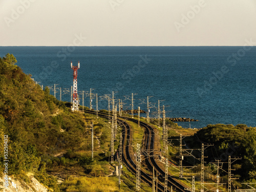 seaside railway landscape: an electrified double-track railway on the seashore and a cell tower on a sunny summer day photo