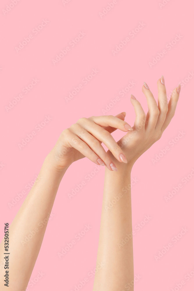 Hands of a beautiful well-groomed with feminine beige nude marble design nails gel polish on a pink background. Manicure, pedicure beauty salon concept.