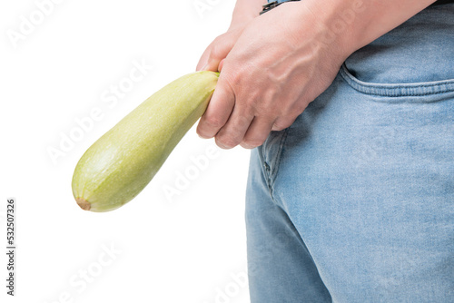 Man crop view holding zucchini as penis at crotch level imitating erectile dysfunction