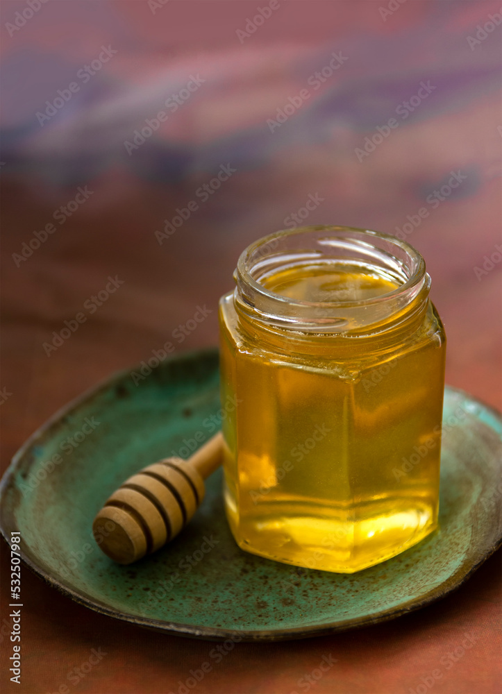 Jar of honey served on plate with honey dipper Jar of honey served on plate with honey dipper