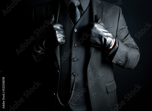 Portrait of Mysterious Man in Black Suit and Gloves. Concept of Mafia Hitman or Hotel Concierge.