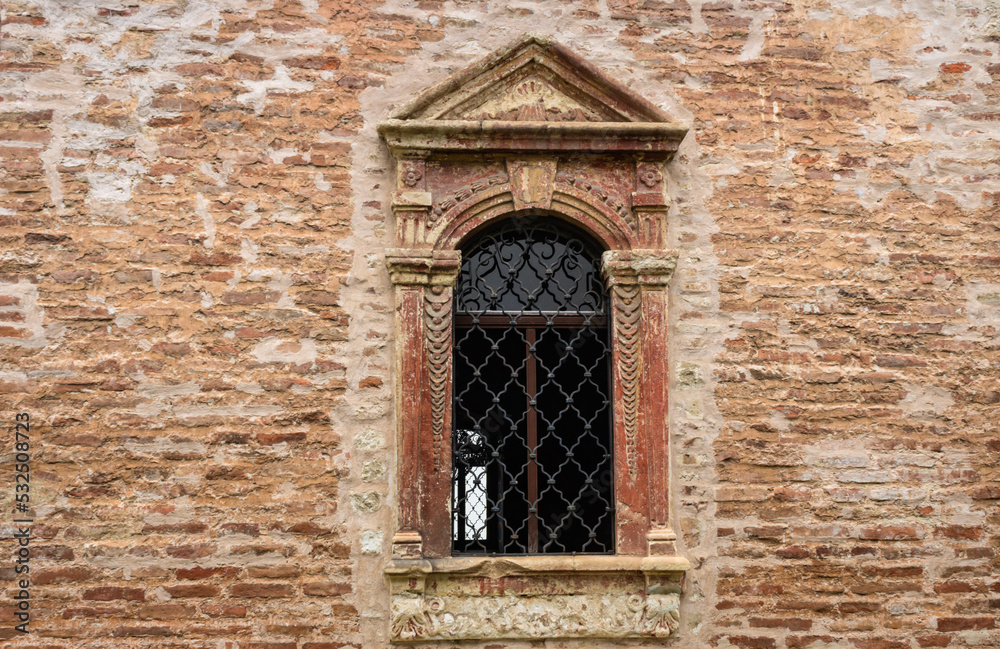 An antique orthodox monastery window with wrought iron on an orange brick wall