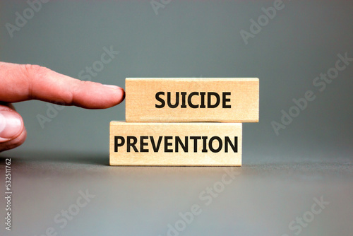 Suicide prevention symbol. Concept words Suicide prevention on wooden blocks. Beautiful grey table grey background. Psychologist hand. Psychological and suicide prevention concept. Copy space.