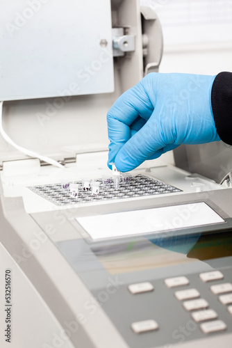 Closeup of a scientist hand while working at the laboratory with a thermal cycler. Polymerase chain reaction technique. PCR technique