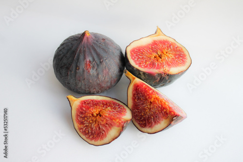 Photo of a fig close-up on a white background. Ripe fruit whole and in pieces.