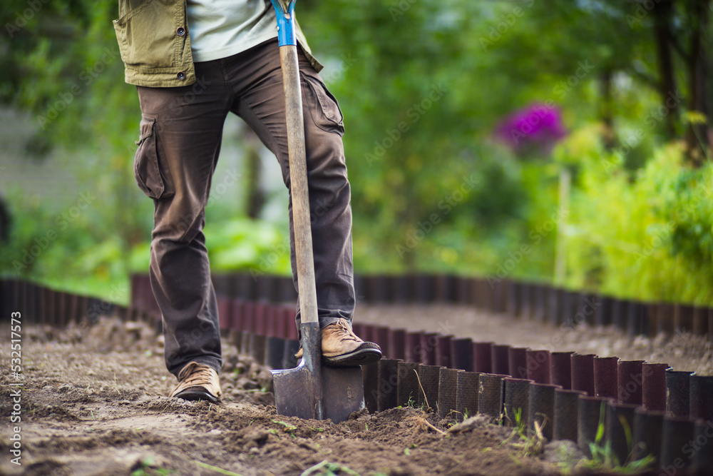 The farmer stands with a shovel in the garden. Preparing the soil for planting vegetables. Gardening concept. Agricultural work on the plantation The farmer stands with a shovel in the garden. Preparing the soil for planting vegetables. Gardening concept. Agricultural work on the plantation