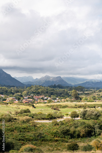 Beautiful countryside of Asturias. View of a small village near to LLares city. In background "Picos de Europa" mountains. Cloudy day. Green landscape. 