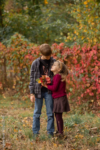 brother and sister are looking at each other and smiling in the autumn park 