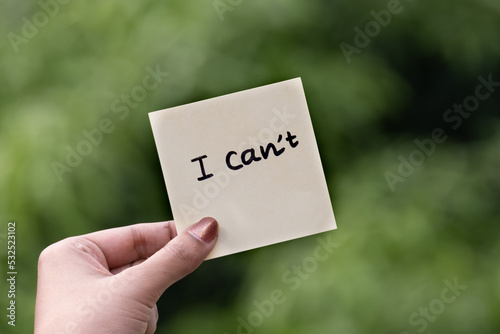 Outdoor image of I can't word written on sticky note green dark blurred background.