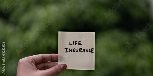 Life insurance concept image which is written on note pad or sticky note outdoor.